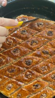 Нанесение сиропа или глазури на горячую пахлаву маленькой ложкой, смазка каждого ромбика для баланса сладости.