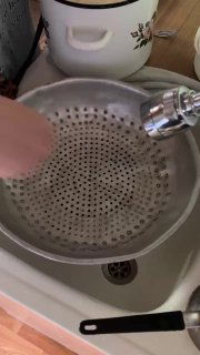 Дуршлаг и металлическая миска на кухонной поверхности — подготовка к отцеживанию отваренного теста, бытовая посуда и руки в кадре.