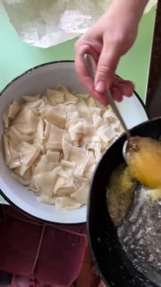 Ложка поливает отваренные кусочки теста растопленным сливочным маслом — сочетание масла и горячих кусочков для подачи татар бераги.