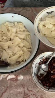 Порция отваренных кусочков теста в миске рядом с отдельной миской жареного лука — готовая подача татар бераги со сметаной по вкусу.