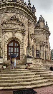 Крупный план жерла и входной части Знаменской церкви: арочные окна, ступени и люди с зонтами на фоне каменной отделки.