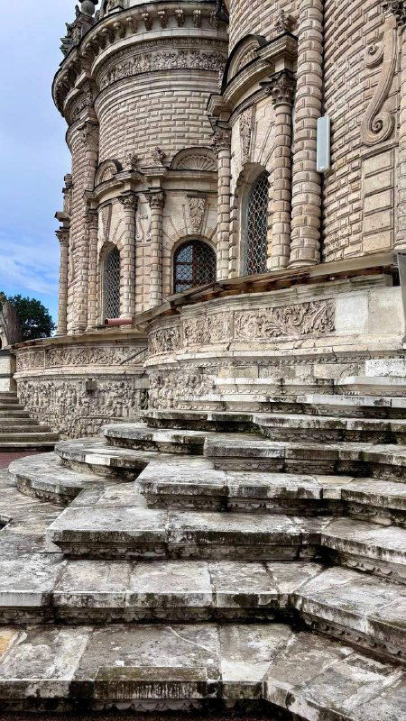 Боковой фасад Знаменской церкви с арочными окнами и массивными ступенями, видно фактуру старинного камня и архитектурные рельефы.
