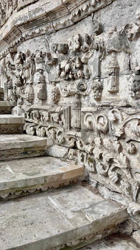 Крупный план ступеней с резными и барельефными элементами на территории усадьбы, видны орнаменты и следы времени на камне.