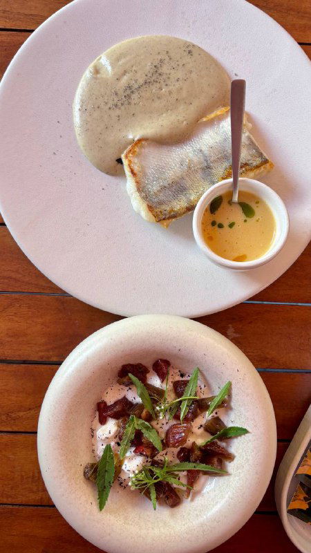 Белая тарелка со страчетеллой или нежной закуской и маленькой чашкой с соусом; кадр подчёркивает текстуру блюда и минималистичную подачу.