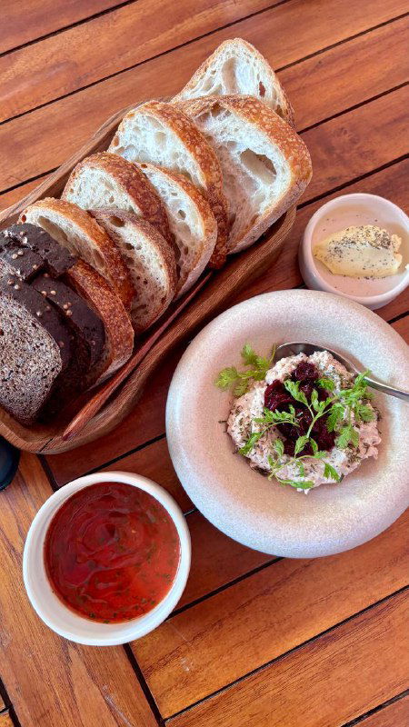 Большая тарелка с порцией: запечённая птица, картофель, зелень и две соусницы — вид сверху на насыщенную и колоритную композицию блюда.