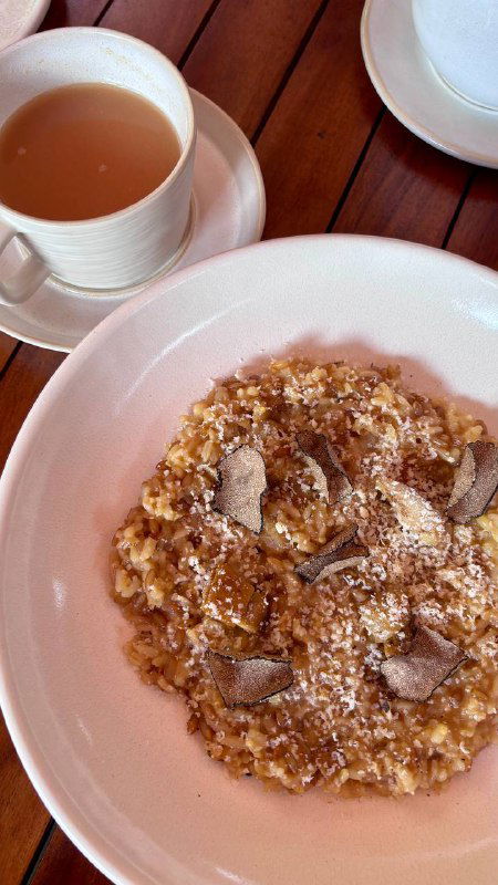 Хлебная тарелка и мисочка с закуской на деревянном столе; рядом чашки и соусы — уютный элемент сервировки перед основными блюдами.