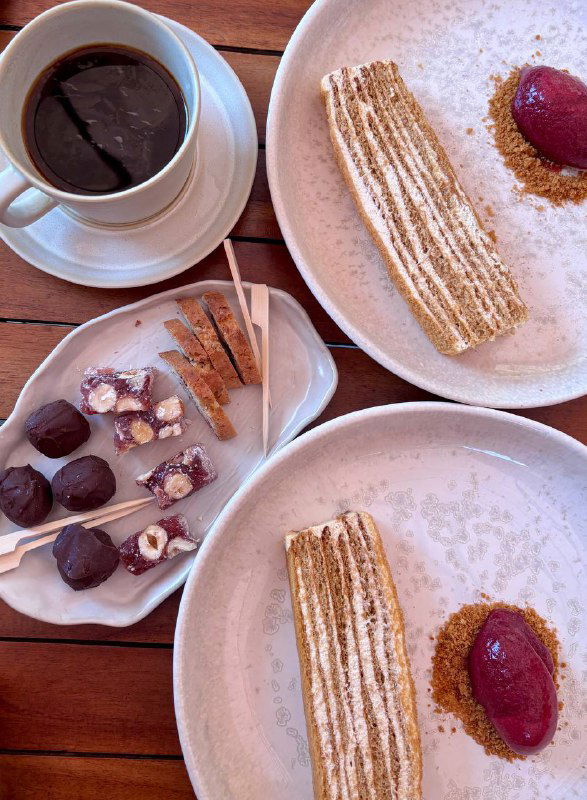 Крупный кадр тарелки с десертом: текстурная крошка, сироп и ягодный сорбет — светлая сервировка и чашка кофе рядом.