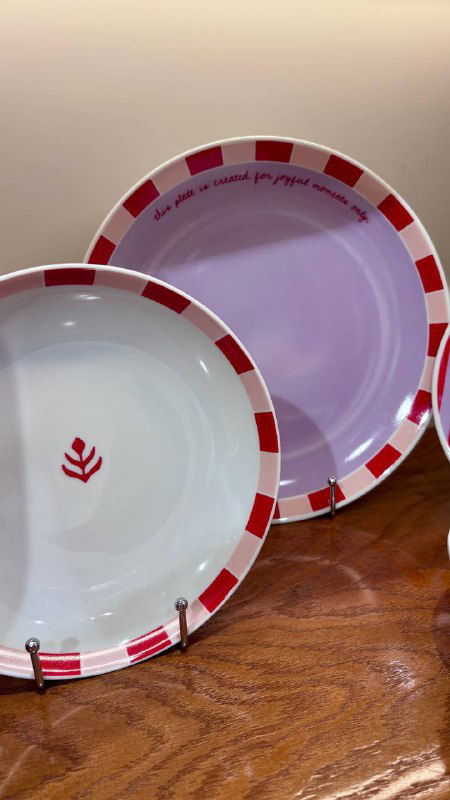 Крупный план декоративных тарелок пастельных тонов на полке в магазине-корнере Nuself: узоры, форма и цвет в фокусе, предметы декора для дома.