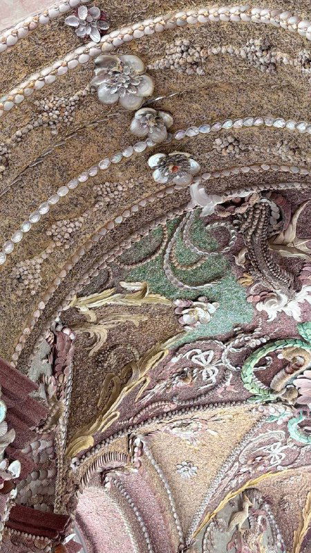 Крупный план украшения из ракушек и перламутра в гроте Кусково: сложный узор, текстура и мерцание материалов в декоративной отделке.