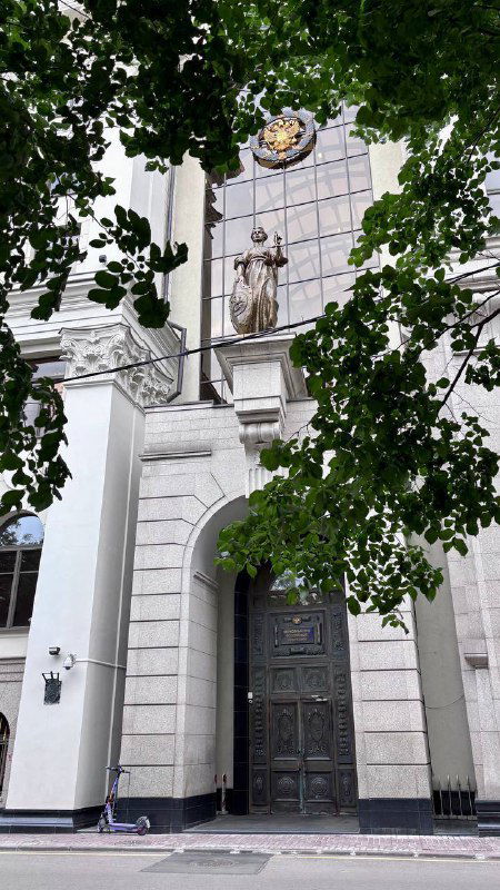 Великолепная статуя Фемиды на фасаде здания Верховного суда, окружённая листвой и архитектурными деталями — городская достопримечательность.