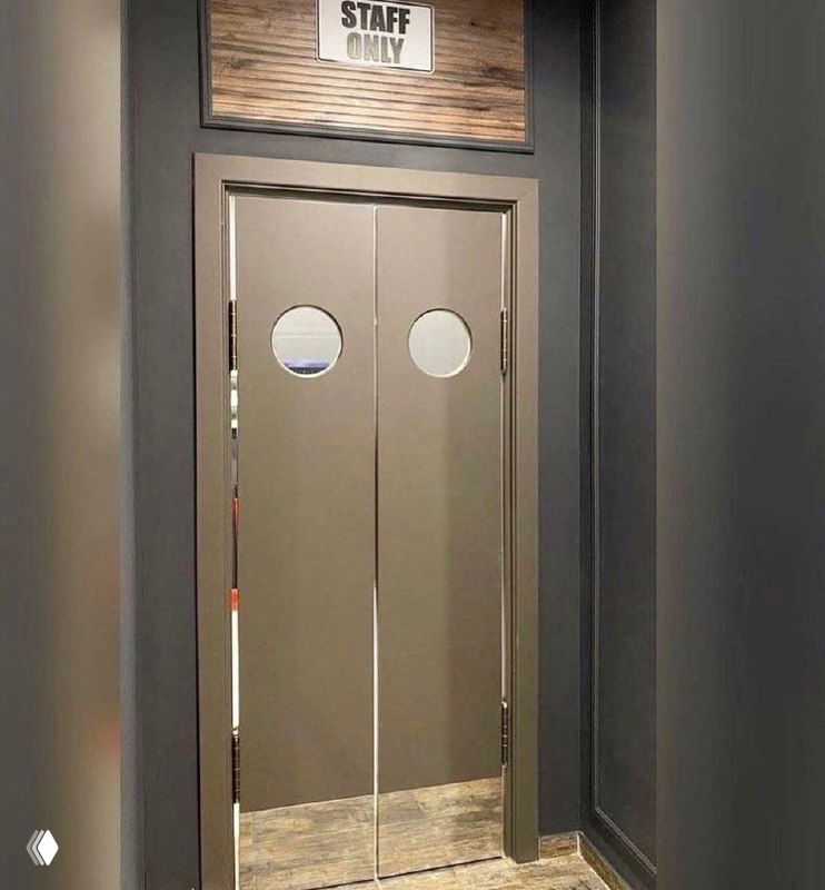 Двухстворчатые маятниковые двери серого цвета с округлыми окнами и табличкой «STAFF ONLY» над проёмом: коридор с тёмными стенами и отражением помещения в стеклах иллюминаторов.