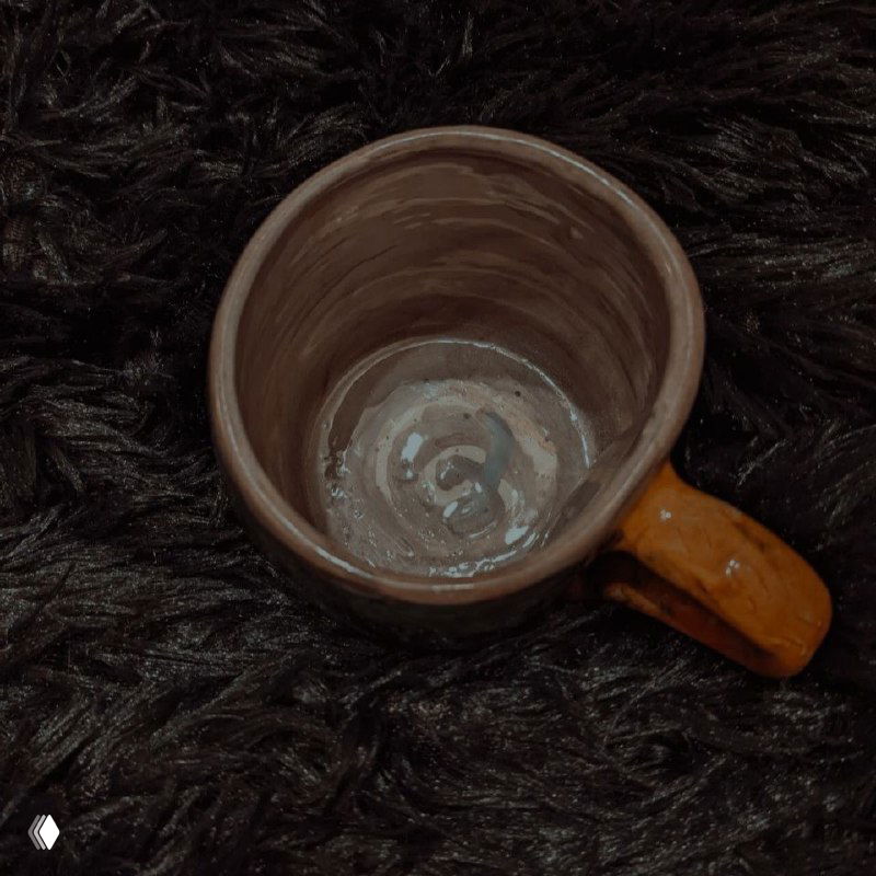 Вид сверху внутренняя часть кружки с глазурью, тёмно-коричневая и с более светлыми разводами, демонстрирующая технику покрытия внутри изделия.