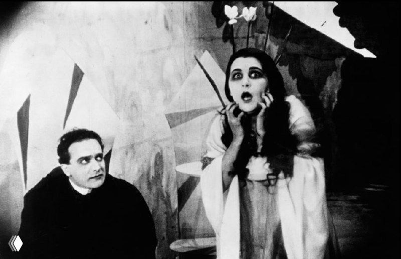 Два персонажа в сцене с сильной мимикой и гримом, женщина в театральной позе — пример гиперболизированной актёрской игры немого кино.