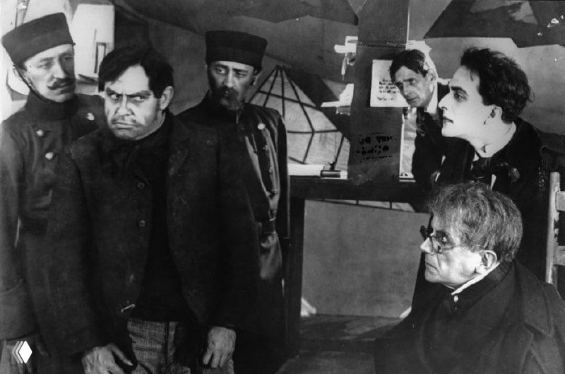 Группа мужчин в костюмах эпохи в напряжённой сцене, чёрно-белый кадр с контрастной светотенью, характерный для раннего кино.