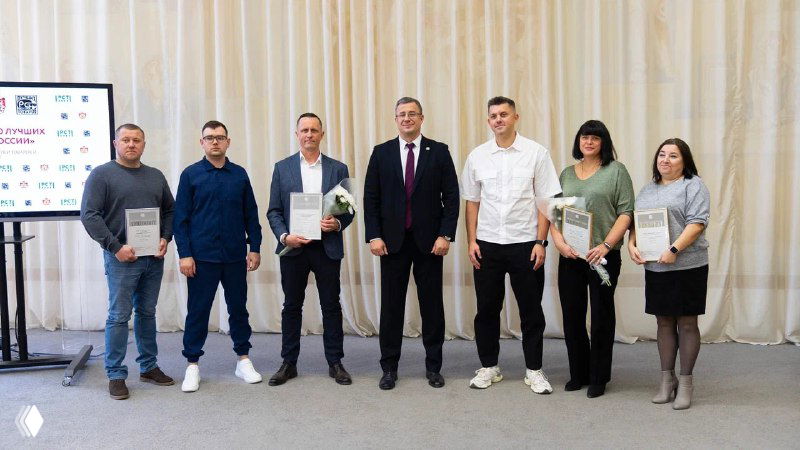 Группа лауреатов и организаторов на сцене с дипломами и вручением наград в официальной обстановке — фото с церемонии награждения.