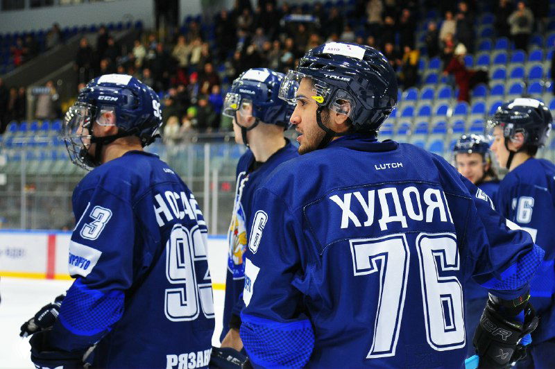 Игроки «Рязань-ВДВ» на скамейке и в центре внимания тренерский штаб, видно пронумерованные фамилии на спинах хоккеистов