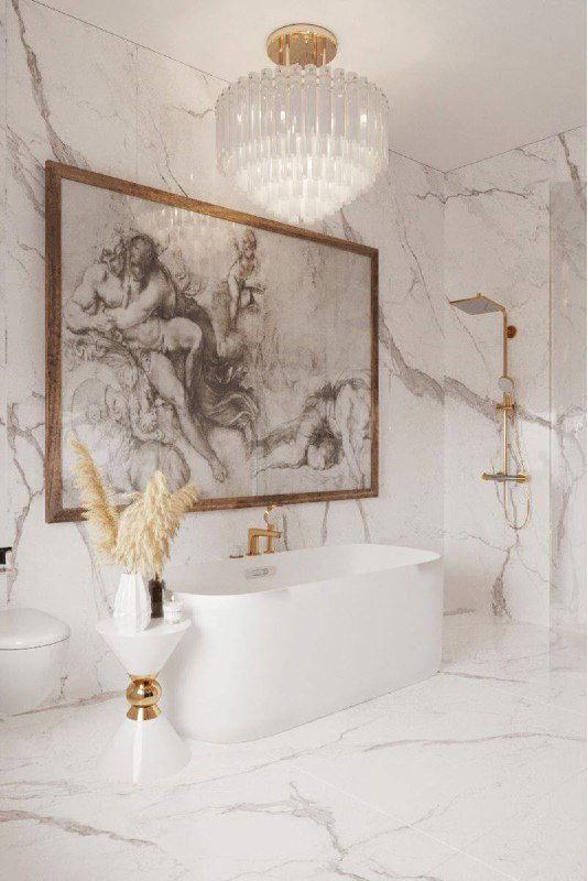 Роскошная мраморная ванная с отдельно стоящей ванной и большим графическим рисунком в раме над ванной, золотые смесители и элегантный декор.