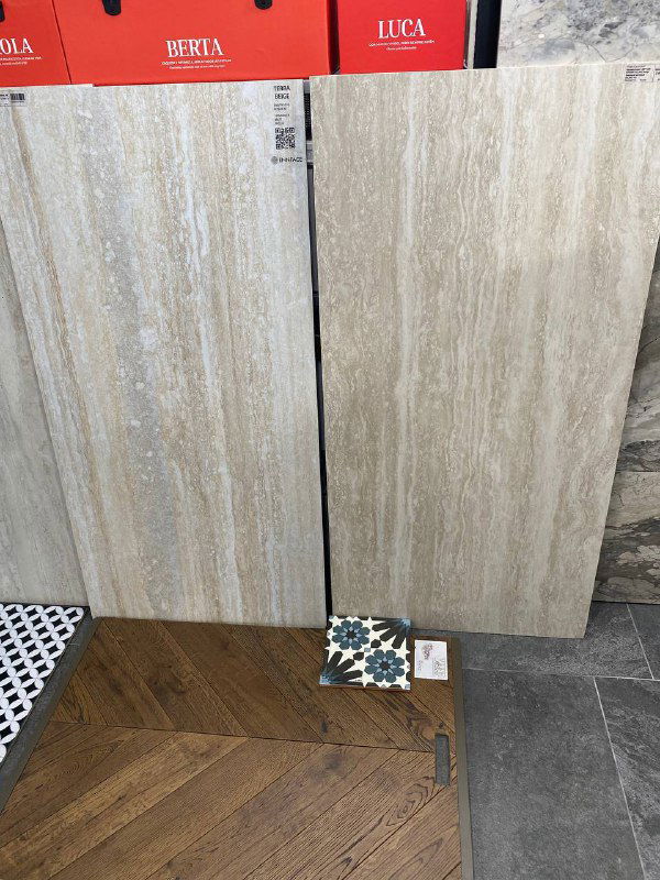 Фото образцов плитки и керамогранита: итальянский травертин-эффект рядом с образцом узорчатой плитки «ромашки» и деревянным декором пола.