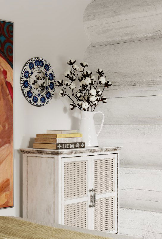 Прикроватная композиция: белая тумба с плетёными фасадами, ваза с ветками, декоративная тарелка и стопка книг на фоне светлой деревянной стены.