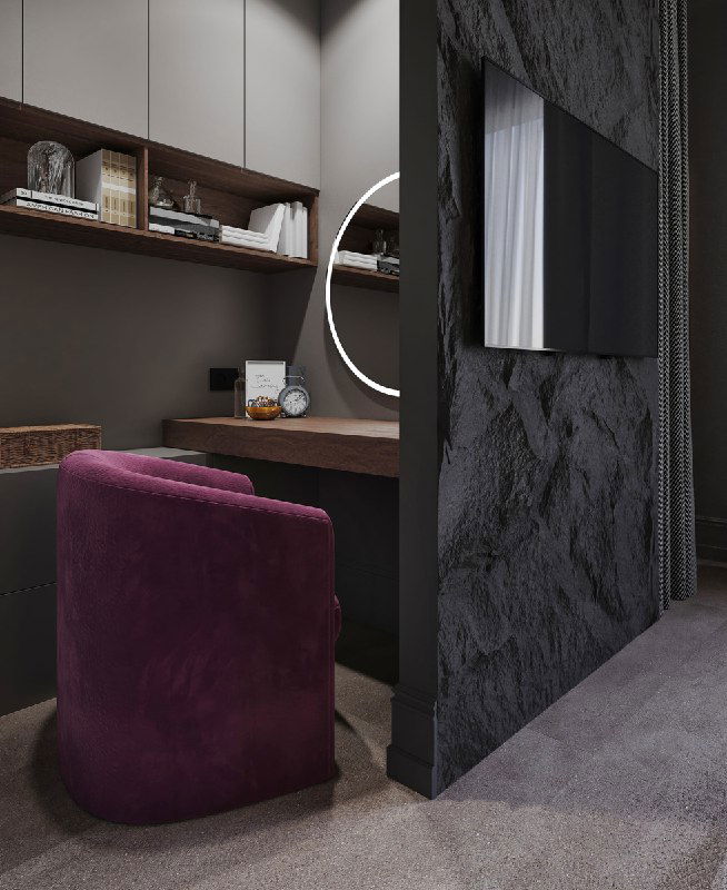 Рабочая зона за перегородкой: деревянный стол, подсвеченные полки и уютное кресло винного оттенка, показывающие компактный кабинет в спальне.