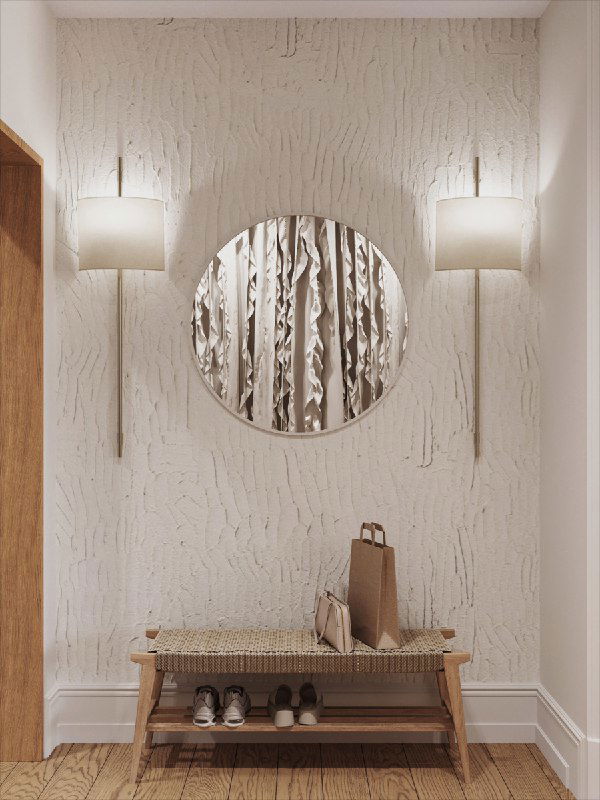 Фактурная штукатурка, круглое зеркало и плетёная скамья у входа: тёплая натуральная палитра, выраженная текстура и комфортная зона ожидания у входа в квартиру.
