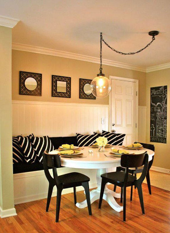 Небольшая столовая с круглым столом и ретро-лампой на цепочке; открытая проводка обыграна как декоративный ретро-элемент интерьера.