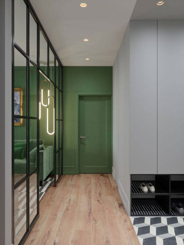 Длинная прихожая с деревянным полом, чёрной стеклянной перегородкой, встроенными обувницами и зелёной дверью в глубине.