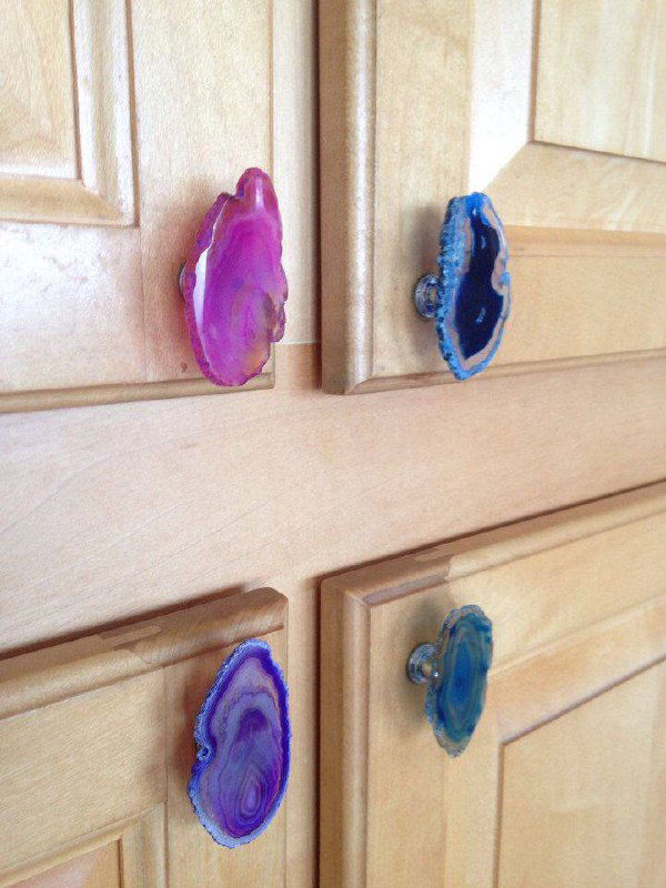 Набор ручек-агатов с разноцветными срезами минералов, аккуратно закреплённых на дверцах из светлого дерева — эффектный декоративный акцент.