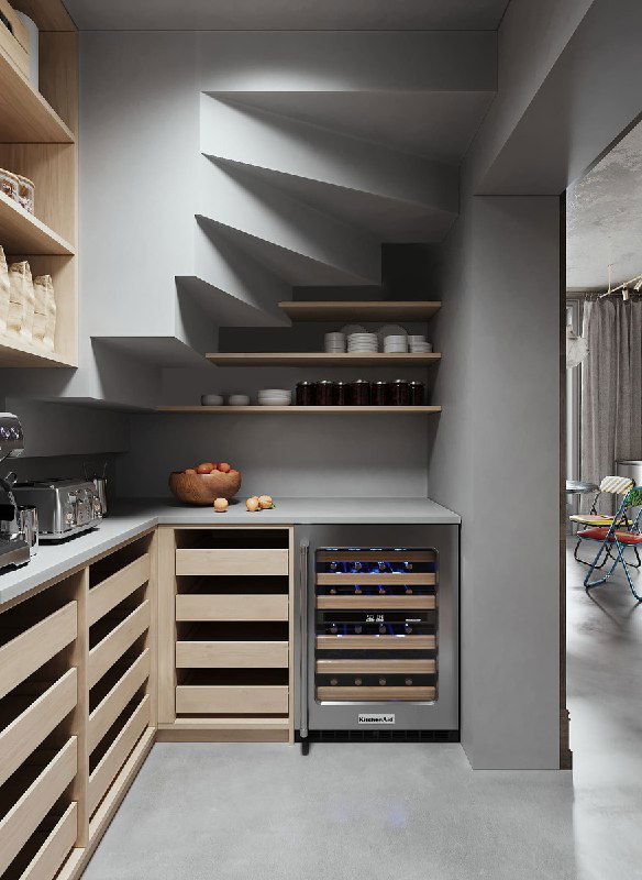 Вид уголка кладовой: рабочая столешница, полки с банками и бутылками, встраиваемый винный шкаф и места для сезонных запасов и техники.