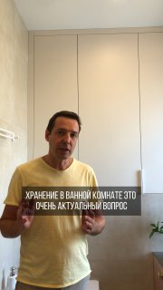 Мужчина стоит в ванной на фоне высокой плиточной стены и встроенных неглубоких шкафчиков; демонстрация идеи хранения и скрытия коммуникаций для порядка.