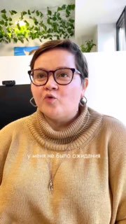 Крупный план авторки — женщина в очках и тёплом свитере на фоне зелёной интерьерной стены и окна; скриншот из видео процесса обсуждения планировки.