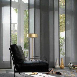 Темные полупрозрачные японские шторы на панорамных окнах; интерьер с кожаным креслом и напольной лампой создает камерную атмосферу.