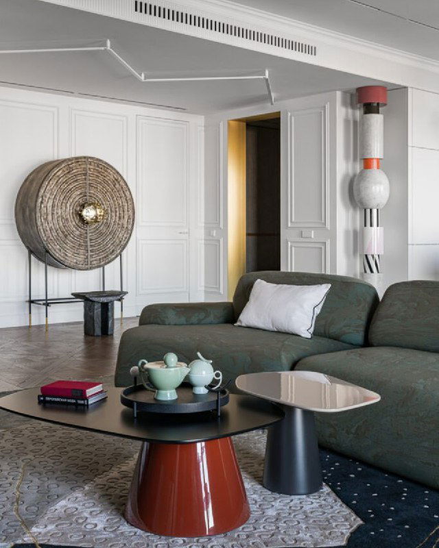 Гостиная с зелёным диваном и декоративными предметами; видно аккуратный дверной проём и интерьерные столики рядом.