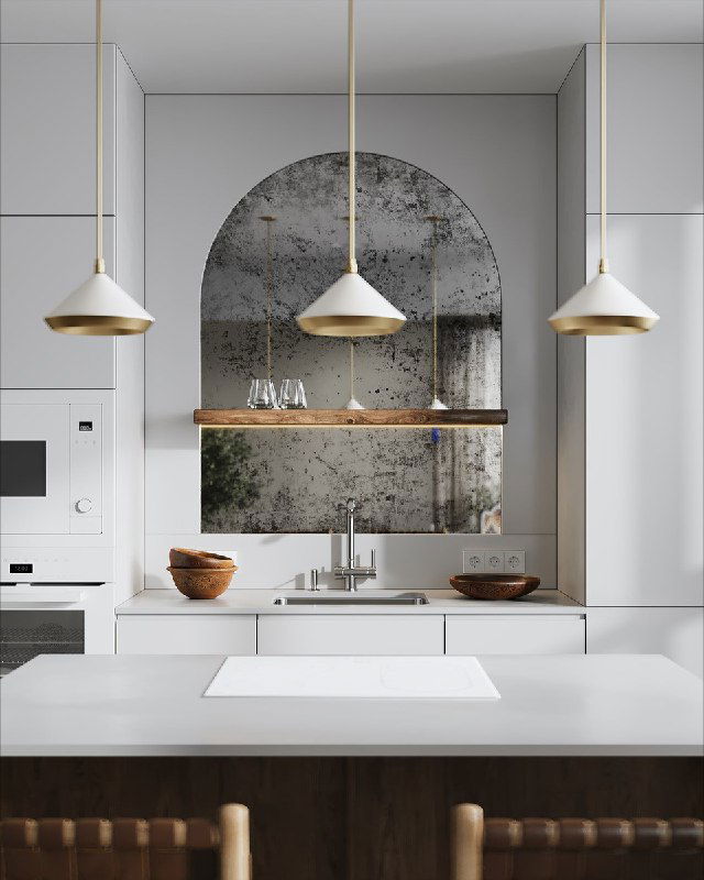 Арочное зеркало, встроенное в кухонный фартук, отражает рабочую зону и добавляет глубины светлой современной кухне с подвесными светильниками.