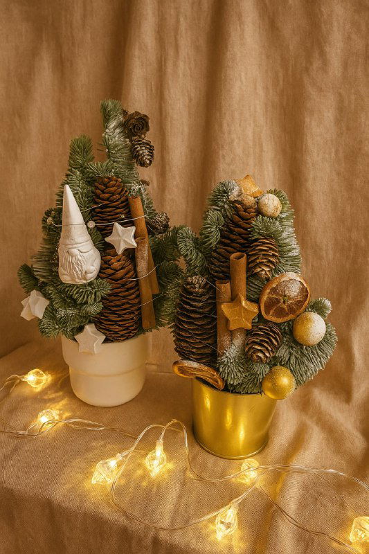 Две конические новогодние композиции из хвои, шишек, засушенных апельсинов и золотых украшений на праздничном фоне