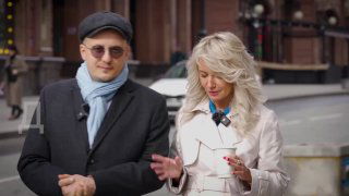 Превью мини‑фильма: двое людей беседуют на городской улице — мужчина в тёмной кепке и шарфе, женщина в светлом пальто; кадр интервью на фоне города.