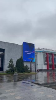 Фасад и наружный экран ЦДП в дождливую погоду с рекламой бизнес-форума «Продажи. Главное» — входная зона и мокрый тротуар на фото.