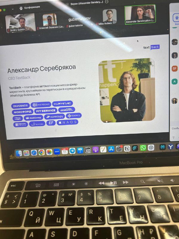Фото экрана ноутбука со слайдом и профилем спикера Александр Серебряков (TextBack): карточка спикера и элементы интерфейса трансляции видны на экране.