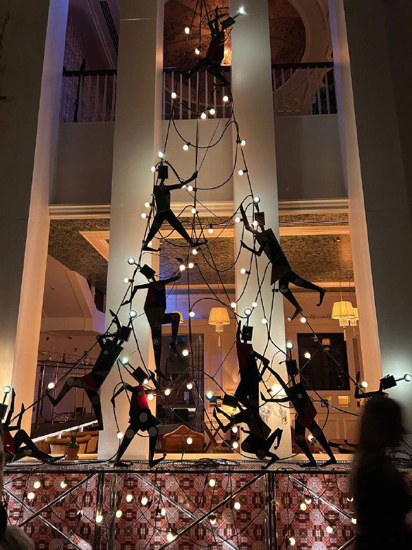Художественная инсталляция или декоративная композиция в просторном интерьере — силуэты людей и подвесные элементы создают выразительный декоративный фрагмент.