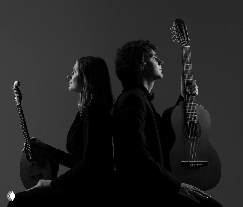 Дуэт музыкантов в профиль с гитарами на чёрно‑белом фото: контрастный портретный кадр, создающий атмосферу камерного концерта.