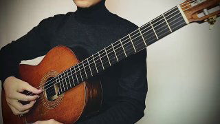 Фотография: музыкант держит классическую гитару — видны торс, гриф и правая кисть; акцент на позиции и технике правой руки.