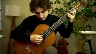 Музыкант играет на классической гитаре в комнате; видно корпус инструмента, правую руку у струн и положение пальцев для тембра.