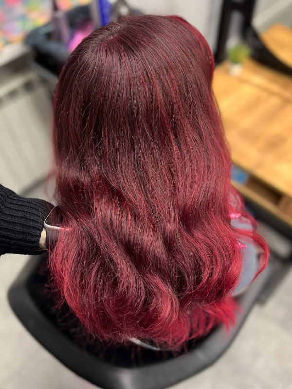 Темно‑бордовые волнистые волосы средней длины после окрашивания в студии HairPositive, кадр показывает текстуру, объем и естественный блеск локонов.