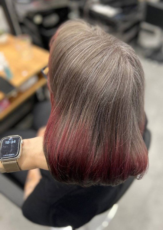 Вид сзади на волосах после процедуры, добавлены красные кончики на фоне седых корней, демонстрация результата окрашивания в салонном освещении.