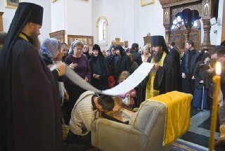Сцена в храме: верующие и священники, один человек наклоняется и прижимает голову к креслу во время земного поклона, акт почитания и духовной практики.