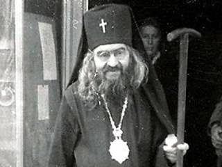Портрет святителя Иоанна Шанхайского в митре с крестом и опорным посохом в руке; старое чёрно‑белое фото, акцент на образе и посохе.