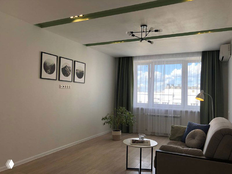 Гостиная с минималистичным оформлением: диван, журнальный столик и растения, фотография демонстрирует актуальный вид комнаты для объявления.