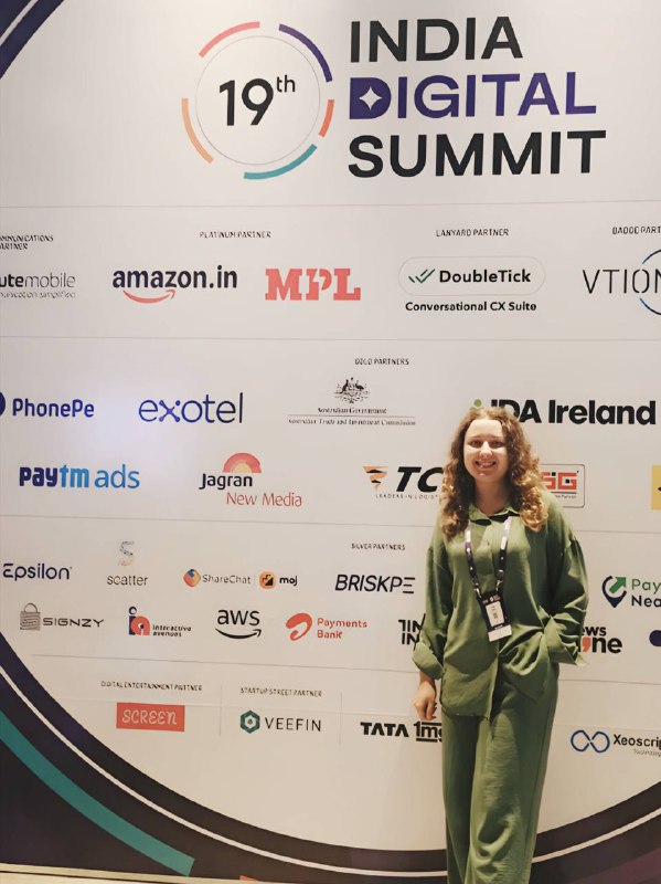 Элина Папас у баннера India Digital Summit с логотипами спонсоров — фото с саммита по цифровым технологиям, отражающее профессиональную активность IBC.
