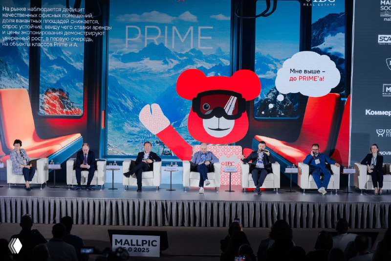 Панельная сессия на MALLPIC 5.0: большая сцена, экран с фирменным медвежонком и несколько участников панели в процессе обсуждения.