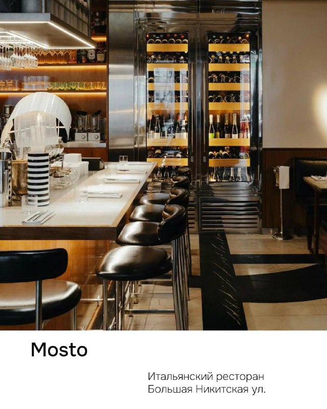 Атмосфера ресторана Mosto: барная стойка, высокие стулья, стеллажи с бутылками вина и приглушённое освещение в современном интерьере.